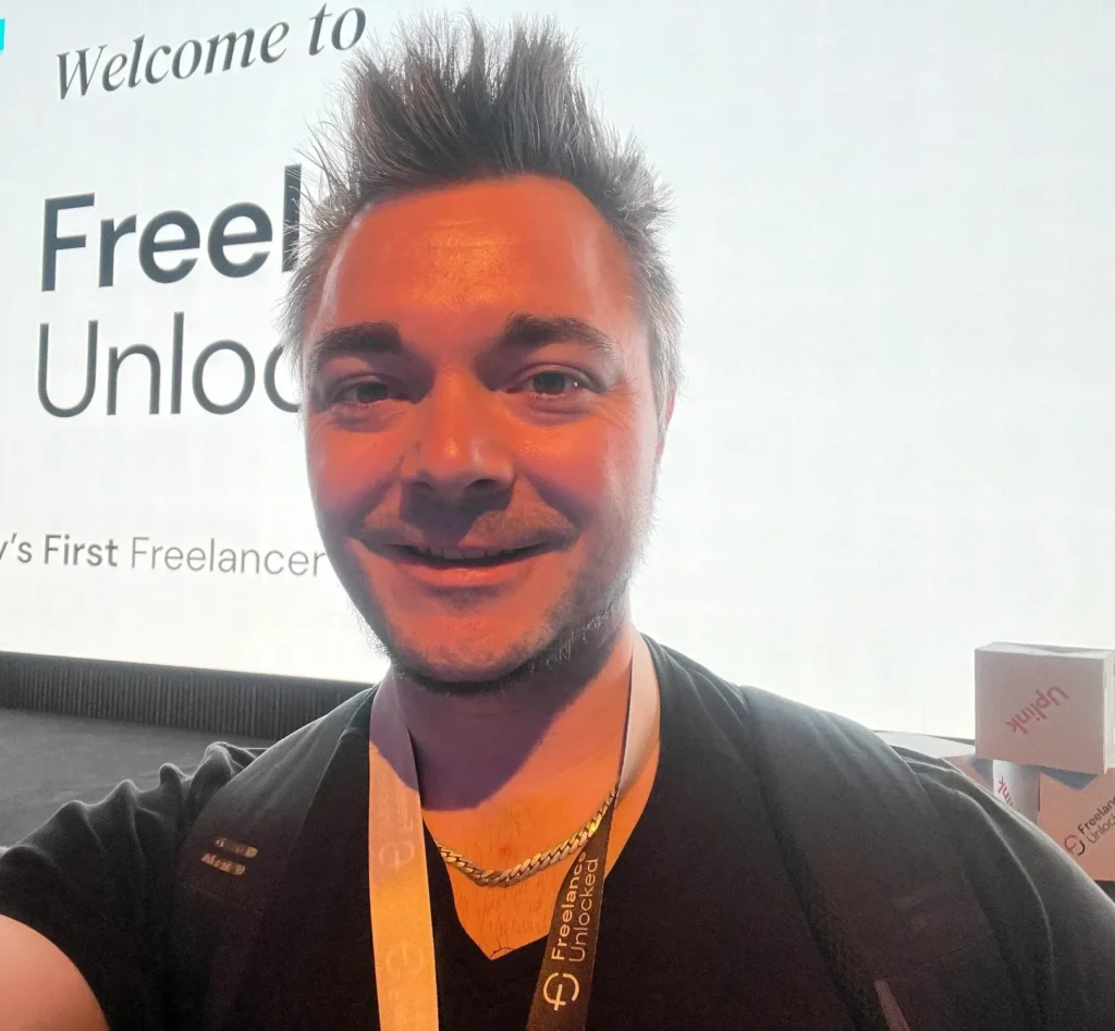 Oli mit Messe-Lanyard vor der Leinwand der Freelance Unlocked