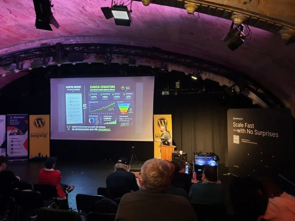 Oli steht am Rednerpult neben einer Leinwand mit seiner Präsentation auf dem WordCamp Leipzig